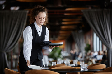 Waist up portrait of young woman as female server setting table in luxury restaurant preparing for opening, copy space