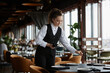© Seventyfour - Portrait of young woman as female server setting tables in luxury restaurant preparing for opening, copy space