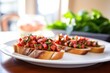 unfocused image of bruschetta on a white plate, sharpened loaf of bread in the foreground