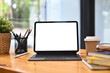 © Prathankarnpap - Front view digital tablet, pencil holder, coffee cup and book on wooden table. White screen for advertising