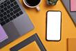 Flat lay, top view smartphone with blank screen, laptop, cup of coffee and book on yellow background