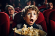 Surprised blonde kid with popcorn watching a horor movie in the cinema.