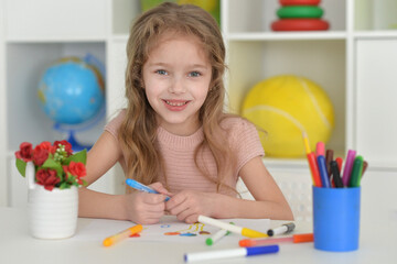 cute girl in the nursery draws at the table