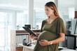 © Malambo C/peopleimages.com - Tablet, happy and pregnant business woman in office reading research information on internet. Maternity, smile and female designer from Canada with pregnancy work on digital technology in workplace.