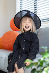 Wall Mural -  A cute girl in a witch hat is laughing at the Halloween party. celebrating Halloween