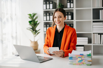 Confident business expert attractive smiling young woman typing laptop ang holding digital tablet on desk in office..