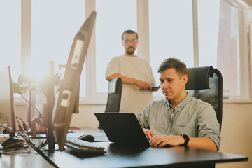 Wall Mural - Portrait of two professional male programmers working on computer in diverse offices. Modern IT technologies, development of artificial intelligence, programs, applications and video games concept