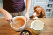 Man and dog together at home in kitchen. Nova Scotia Duck Tolling Retriever watching while his pet owner mixing dough to prepare sweet pie..