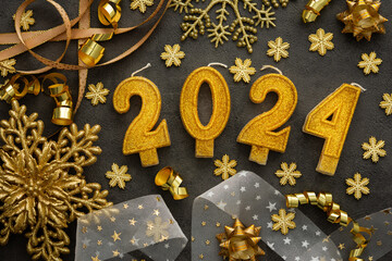 Wall Mural - Merry Christmas and Happy New Year 2024, 2024 cake candles and various holiday decorations and ribbons in gold color on black background