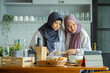 © maya1313 - muslim mother looking at recipe from laptop and cooking with her daughter. having fun woman with hijab and kid preparing dinner together, Islamic Lady With Small Daughter Enjoying Doing Homemade