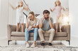 © Clement C/peopleimages.com - Frustrated parents, sofa and headache with children jumping in living room chaos, ADHD or crazy home. Mother and father in stress, burnout or fatigue with busy or hyper active kids in lounge at house
