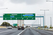 © Austockphoto - truck transporting goods along multi lane road in city with big overhead signs for directions