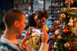 © Marko Geber - Young woman taking pictures of her lesbian partner decorating a Christmas tree at home