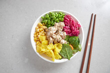 top shot of a bowl of chicken vegetable salad with wooden chopsticks on top grey background