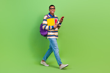 Full body cadre of steps young man with documents wear backpack casual dress code email friends phone isolated on green color background