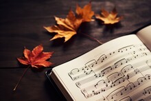Book Of Sheet Music On A Wooden Table With Colorful Autumn Maple Leaves