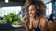 Young athletic woman eats a salad in her plate while eating breakfast