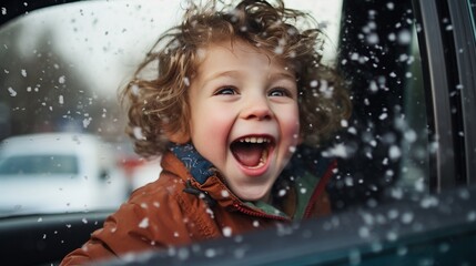 Happy little boy watching and playing with snow from an open car window on the trip of a snowy winter holiday, joyful kid have fun with snow flakes.