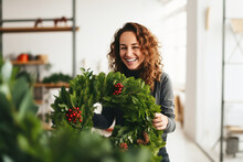 Attractive Woman Florist Creating Natural Christmas Wreath In Flower Shop. Small Business