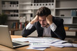 © Jan - Exhausted man, buried in work, showing signs of despair in front of his laptop