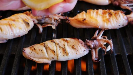 Sticker - Chef's Hand Is Squeezing A Fresh Lemon Over Grilling Squid. Slow Motion. Close up