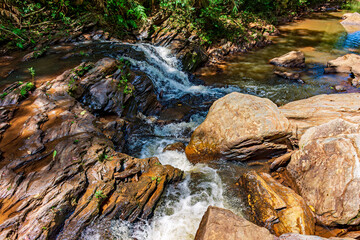 Wall Mural - Stream of calm waters between rocks and surrounded by vegetation