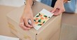 © CineLens/peopleimages.com - Online order, label sticker and woman hand with small business in fashion with delivery and cardboard box. Stock, startup and sales of ecommerce and boutique at home of a entrepreneur with package
