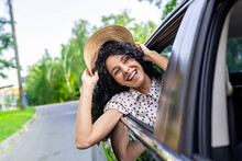 Young Girl Traveling By Car, Hispanic Woman With Curly Hair Looking Out The Window, Enjoying Vacation And Travel.