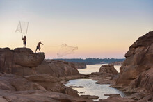 Two Fisherman Standing On Rocks Casting Fishing Nets Into Mekong River, Sam Pan Bok, Ubon Ratchathani, Thailand