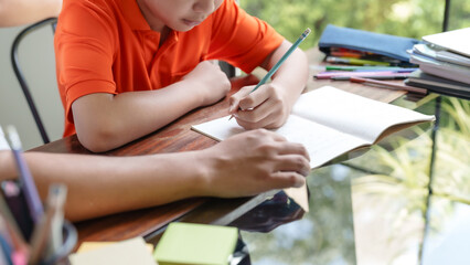 Father helping his son doing homework and writing on notebook while studying education at home