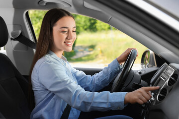 Wall Mural - Choosing favorite radio. Beautiful young woman pressing button on vehicle audio in car