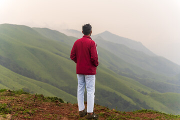 happy young unknown man standing in front of mountain landscape
