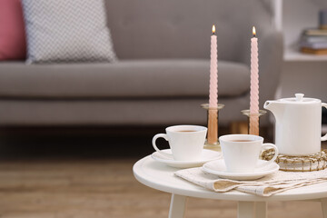 Poster - Cups of tea, teapot and burning candles on white coffee table indoors. Space for text