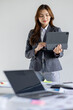 © David - Asian businesswoman hoding digital tablet standing in office isolated on white background, Smiling woman executive manager, Feeling happiness.