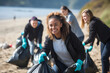 The eco activists in gloves collecting garbage from the seashore. Ocean pollution, environmental conservation and ecology concept. Generative Ai