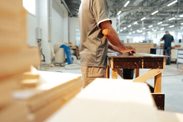 Close up of male carpenter working with piece of wood in a workshop