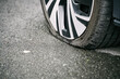 Car wheel flat tire on the road. Punctured vehicle tire. Roadside assistance.