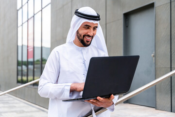 Wall Mural - Arab middle-eastern man wearing emirati kandora traditional clothing in the city - Arabian muslim businessman strolling in urban business centre.