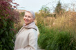 © Anatoliy Karlyuk - Outdoor portrait of senior active lady in coat walking among herbs in fields of city park to stay healthy, breathing fresh cool air, turning head to camera, smiling enjoying stroll