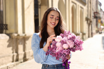 Canvas Print - Beautiful woman with bouquet of spring flowers on city street