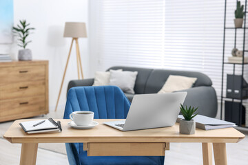 Poster - Home workspace. Laptop, cup of coffee and stationery on wooden desk indoors