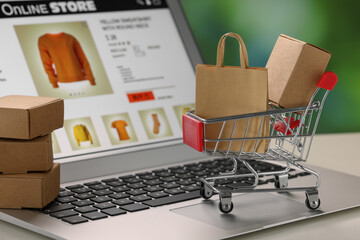 Wall Mural - Mini shopping bag, boxes and cart on laptop, closeup. Online store