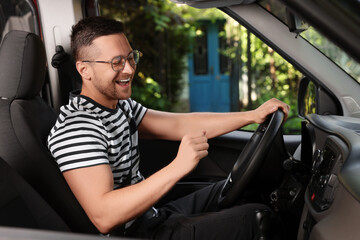 Wall Mural - Listening to radio while driving. Handsome man enjoying music in car