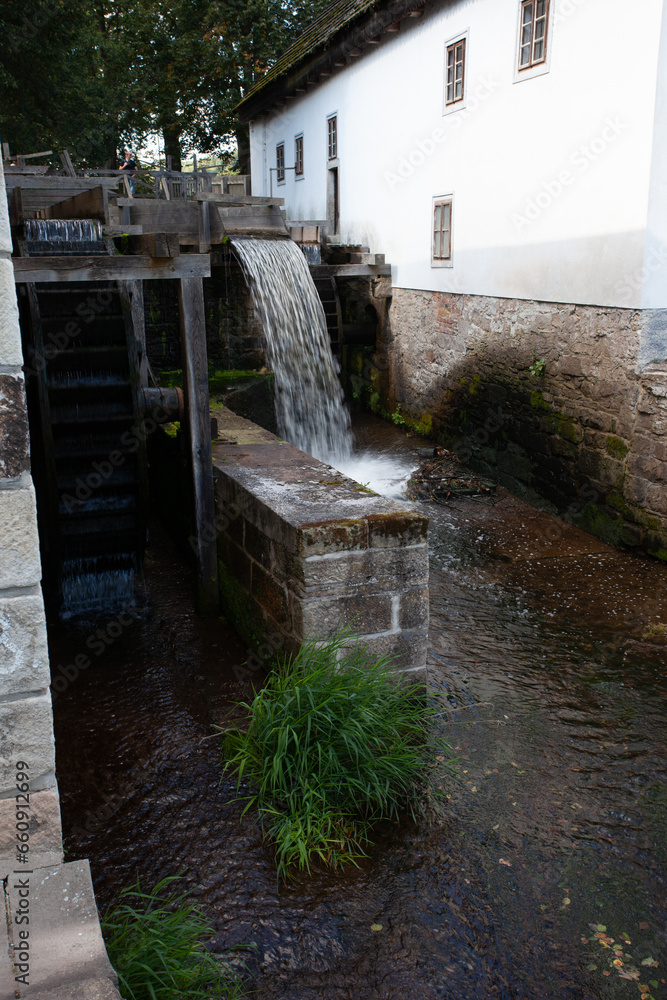 The paddlewheel turns and the water falls, showing the movement. Wooden installations of a water mill to produce wheat flour.
