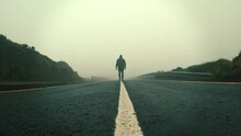 A Man Walking Into The Fog On The Line Of A Lonely Street With A Hood