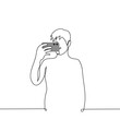 © Kamila Bay - man stands and films on a mobile phone holding the phone horizontally - one line art vector. concept of shooting video or taking mobile photo