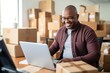 Online store seller during an online conversation with a buyer. Middle aged black man sitting in a warehouse of packaged products and communicates with a customer. Preparing to send an online order.