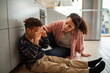 © Marko Geber - Young mixed mother comforting her crying son on the floor at home