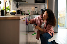 Young mixed woman cleaning her kitchen at home