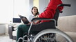 Smiling woman communicates with woman sitting in wheelchair with laptop. Communication with people with disabilities concept